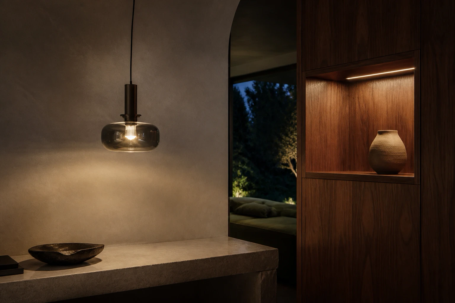 Sculptural smoked-glass pendant beside curved plaster and tailored walnut joinery